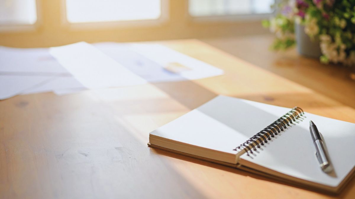 柔らかな光が差し込む机の上に置かれた、開いたノートとペン