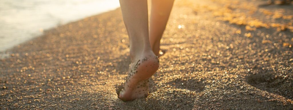 朝日の砂浜を裸足で歩く女性の足元。自分らしい一歩を踏み出す女性のためのライフカウンセリング